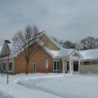A brick house surrounded by snow on a winter day.