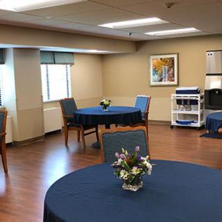 A well-lit dining area with tables and chairs, decorated with small flower arrangements.