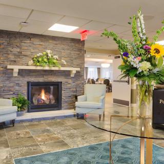 A modern lobby with a cozy fireplace, stylish chairs, and vibrant floral decor.