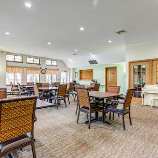 A spacious dining area featuring comfortable tables and chairs, illuminated by bright lighting.