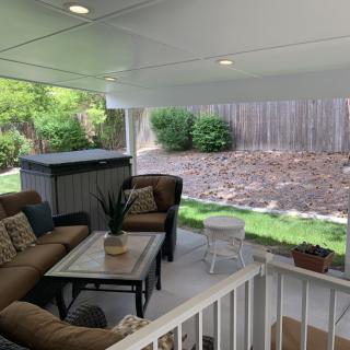A cozy patio area with comfortable seating and a table, overlooking a garden in the backyard.