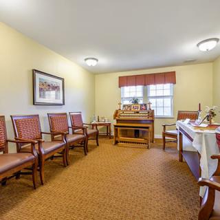A cozy waiting room featuring multiple chairs, a wooden desk, and decorative artwork.