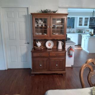 A wooden china cabinet displayed in a dining room setting.