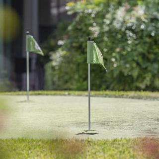 A serene outdoor putting green with two flags in the foreground.