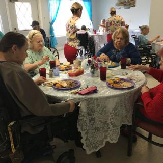 A group of seniors enjoying a meal together in a care home setting.