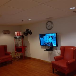 A cozy waiting room with armchairs, a television, and a popcorn machine.