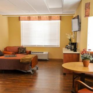 A cozy living room with a sofa, a wall-mounted television, and a small round table with plants.