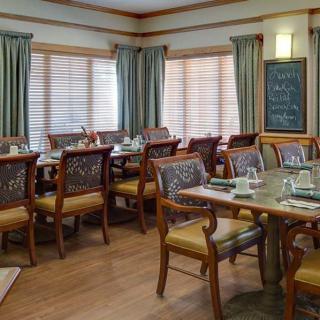 A neatly arranged dining area with multiple tables and chairs, featuring a menu board in the corner.