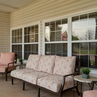 A cozy porch with cushioned seating and decorative plants.
