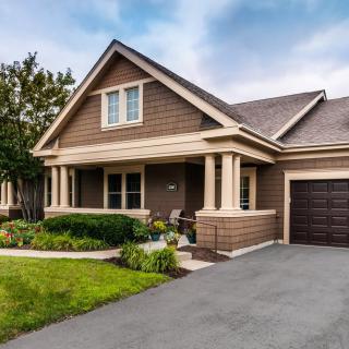 A beautiful suburban house with a porch and well-maintained front yard.