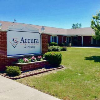 A healthcare facility with a sign reading 'Accura' on a sunny day.