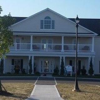 A two-story residential house with a large balcony and a pathway leading to the entrance.