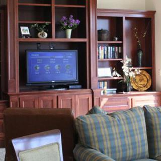 A cozy living room featuring an entertainment center with a TV, bookshelves, and a comfortable sofa.