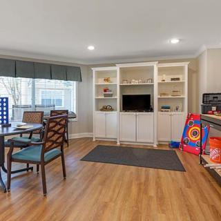 A cozy living room with built-in shelves, a TV, and a play area.