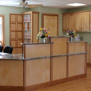 A reception area with a wooden desk and floral decorations.