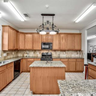 A spacious kitchen featuring wooden cabinets and a central island with granite countertops.
