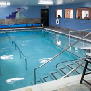 An indoor swimming pool with accessibility features, including handrails and stairs.