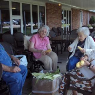 A group of elderly individuals sitting outside and socializing.