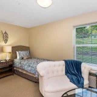 A cozy bedroom with a single bed, chair, and window view.