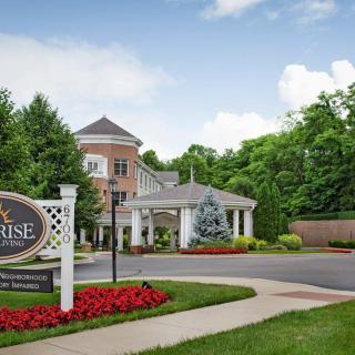 Entrance to a landscaped building with a sign and surrounding greenery.