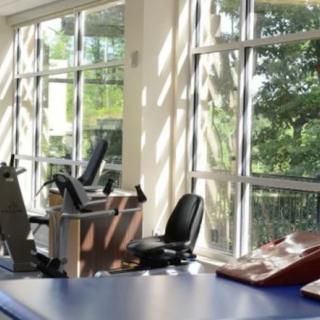 A brightly lit gym with exercise equipment positioned near large windows.