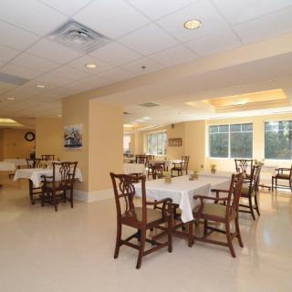 A spacious dining room area with neatly arranged tables and chairs under soft lighting.