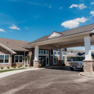A welcoming entrance to a modern residential or commercial building, featuring a spacious parking area under a clear blue sky.