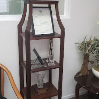 A wooden shelf displaying a certificate and decorative items.