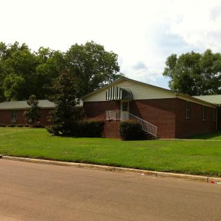 A brick building surrounded by trees and a well-maintained lawn.