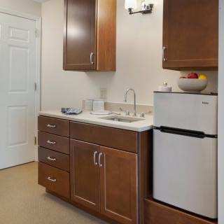 A compact kitchen area with wooden cabinets, a sink, and a small refrigerator.