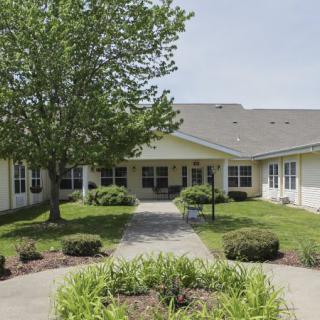 A residential building with a landscaped yard and a pathway leading to the entrance.