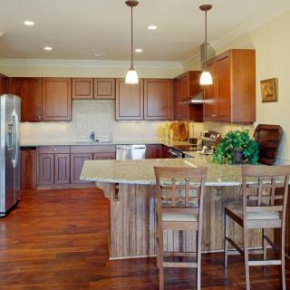 A spacious kitchen interior featuring wooden cabinets and a central island with pendant lighting.