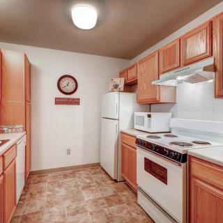 A cozy kitchen with wooden cabinets, white appliances, and tiled flooring.