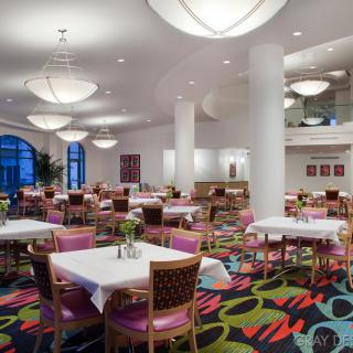 A spacious, modern restaurant interior with colorful carpet and well-arranged dining tables.
