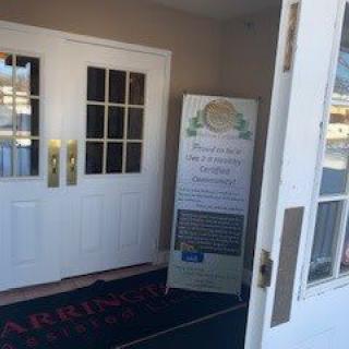 An open entrance door leading to a building, with a sign displayed beside it.