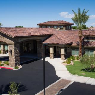 Aerial view of a luxury residential building with landscaped surroundings and palm trees.