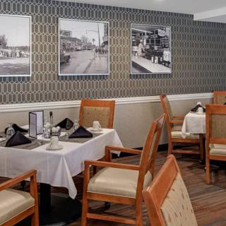 A neatly arranged dining area with tables and chairs, featuring artistic photographs on the wall.