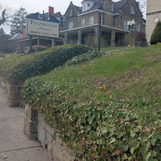 A charming residential building with ivy-covered landscaping and a welcoming sign.