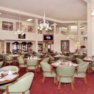 A spacious restaurant interior with neatly arranged tables and green chairs.