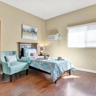 A cozy bedroom with a single bed, armchair, and natural light streaming through the window.