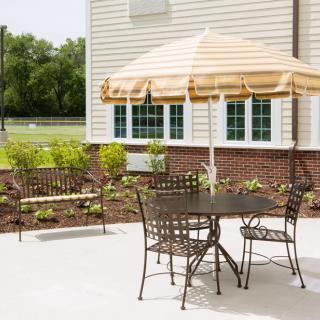 A backyard patio with metal furniture and a striped umbrella.