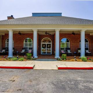 A brick building with large white columns at the entrance and a neatly landscaped area in front.