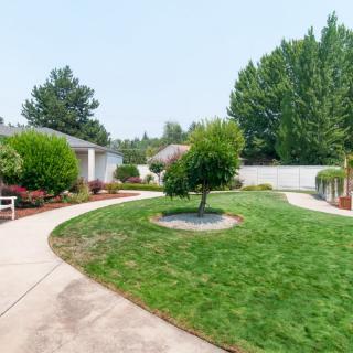 A well-maintained garden with a concrete pathway winding through green grass and trees.