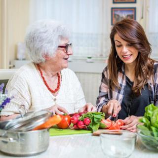 A grandmother and a woman preparing vegetables together in the kitchen.