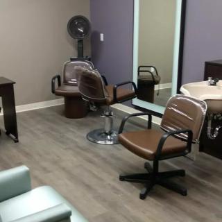 An interior view of a hair salon with chairs, a mirror, and a sink.
