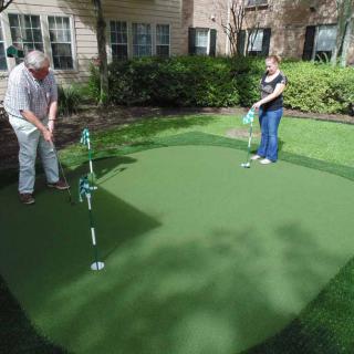 Two people enjoying a game of putting on a backyard green.