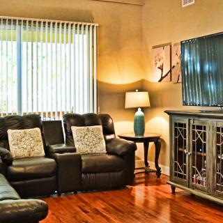 A cozy living room featuring leather sofas, a TV stand, and warm lighting.