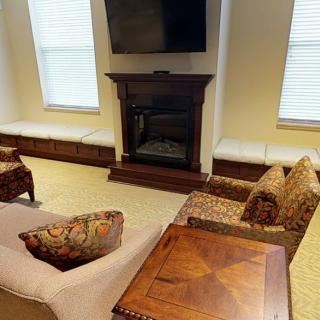 A cozy living room featuring a fireplace, comfortable seating, and a mounted television.