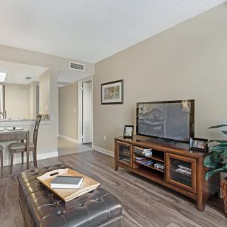 A cozy living room featuring modern furniture, a large TV stand, and elegant hardwood flooring.