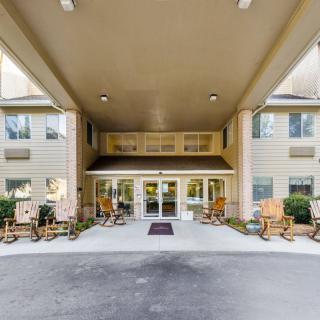 The entrance of a hotel with a covered porch and rocking chairs.